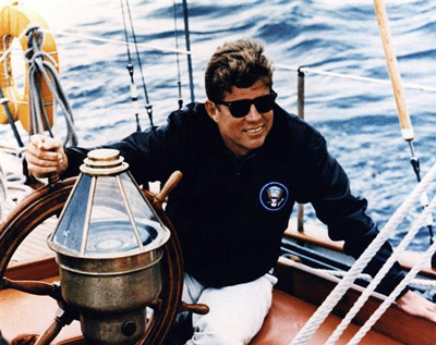 President Kennedy at the helm of the U. S. Coast Guard yawl "Manitou". This was one of his favorite sailing yachts, and there are many White House Diary entries that describe cruising aboard "Manitou" with family and friends. 